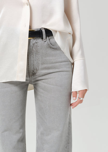 Person wearing a white shirt and gray jeans on a plain background