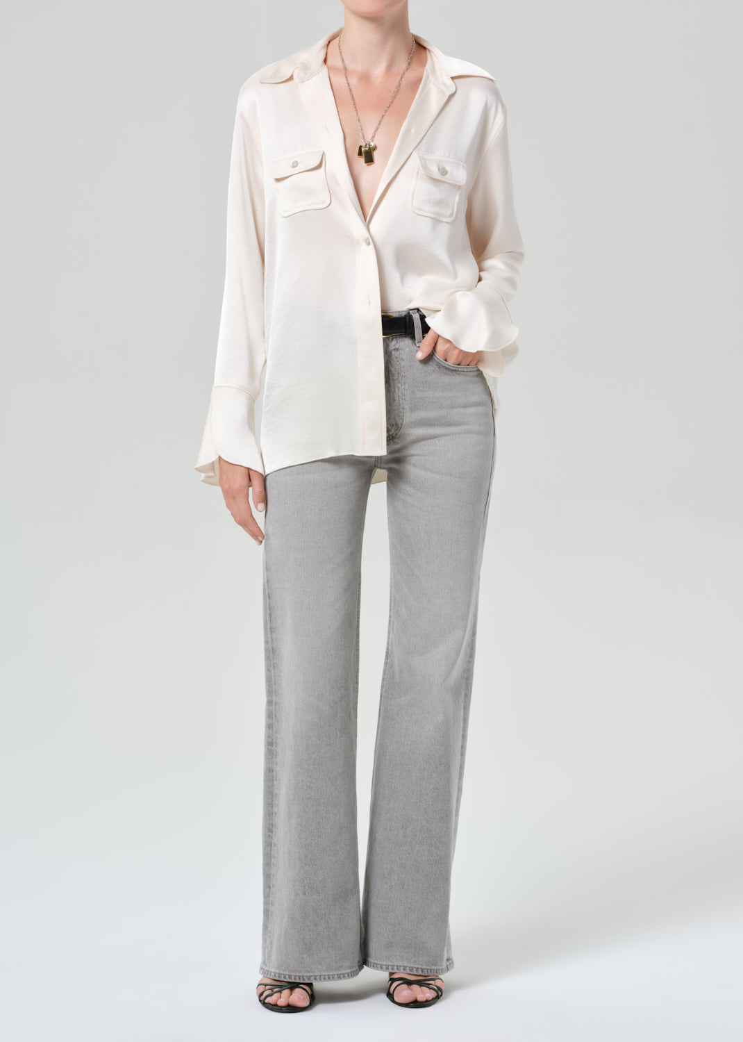 Person wearing a white shirt and gray jeans on a plain background