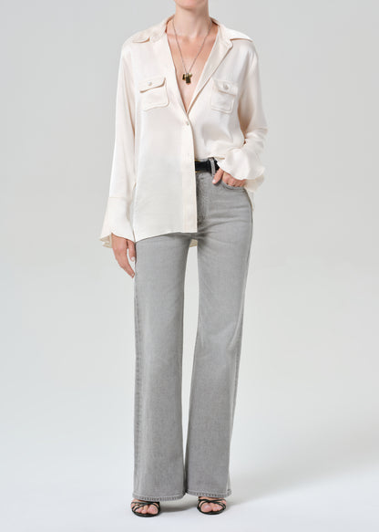 Person wearing a white shirt and gray jeans on a plain background