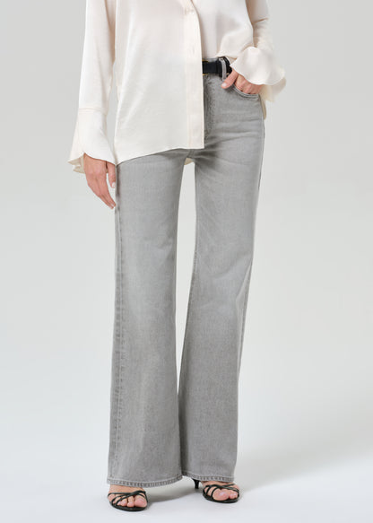 Person wearing a white shirt and gray jeans on a plain background