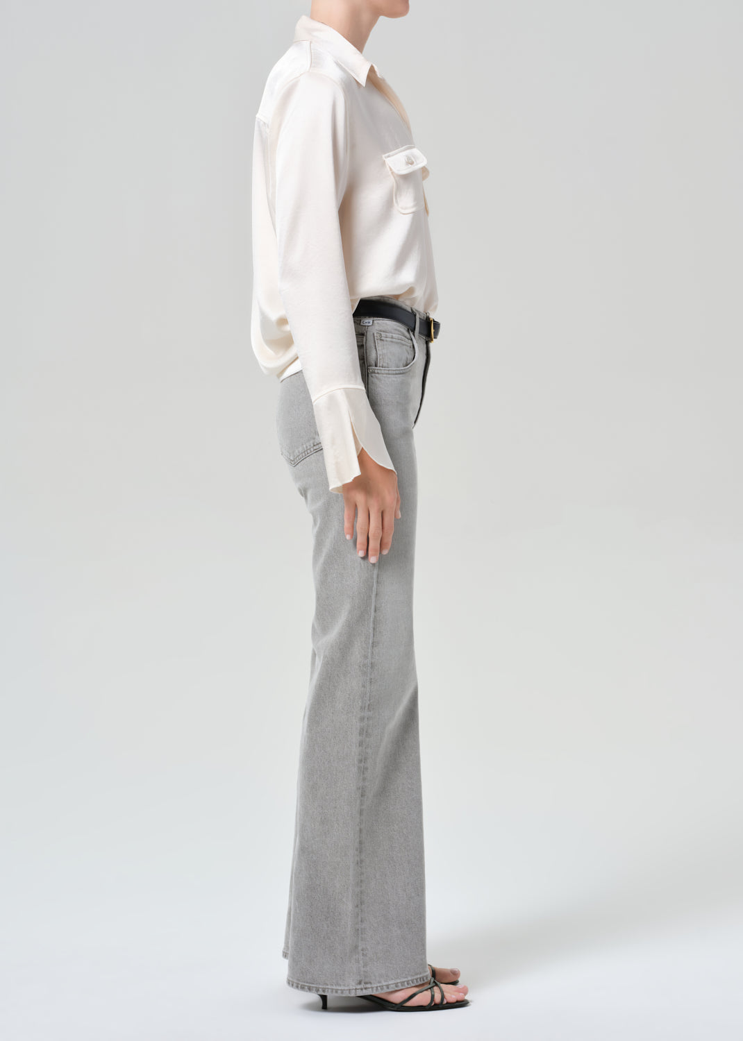 Person wearing a white shirt and gray jeans on a plain background