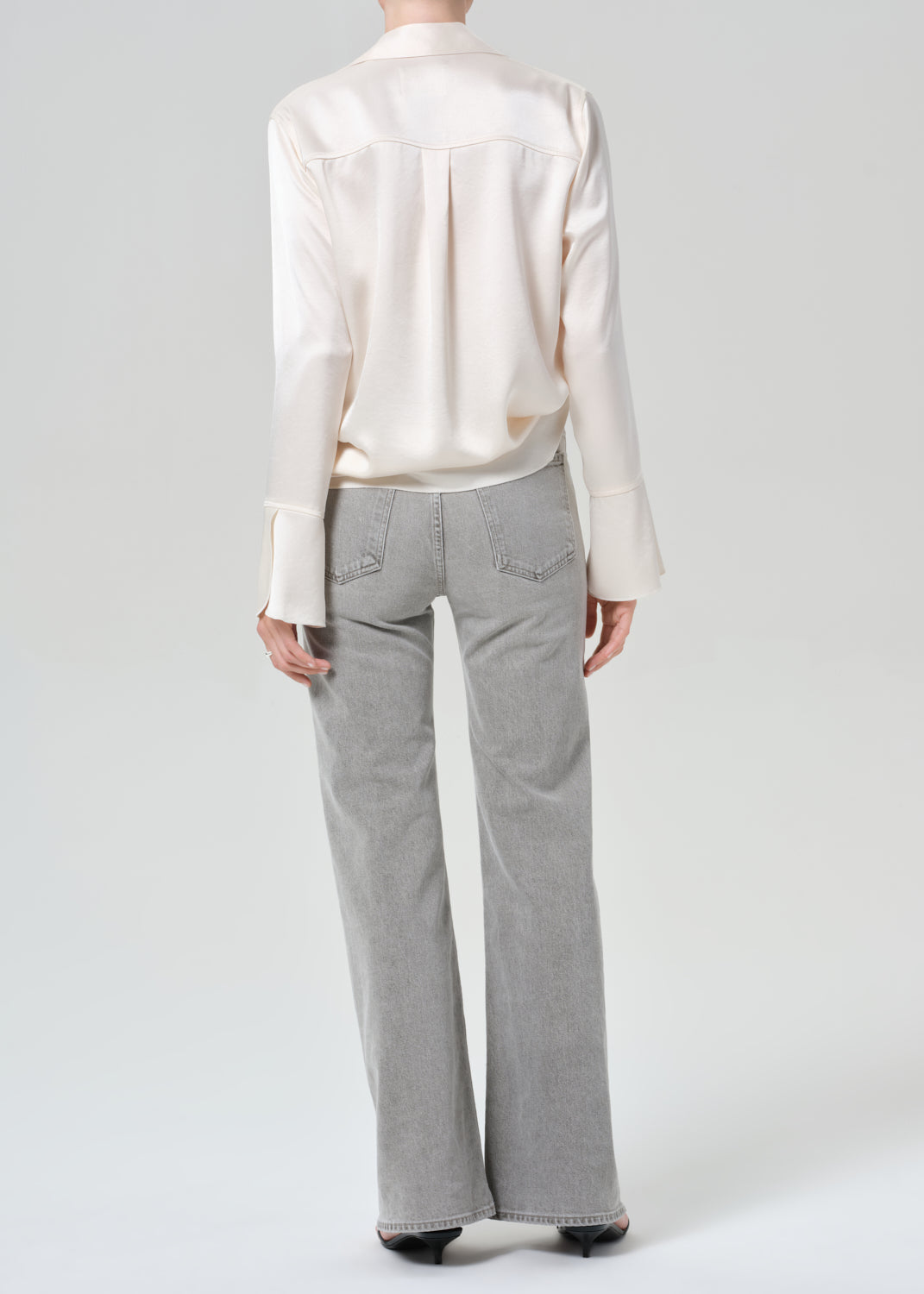 Person wearing a white shirt and gray jeans on a plain background