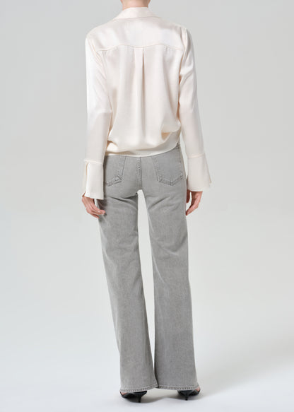 Person wearing a white shirt and gray jeans on a plain background