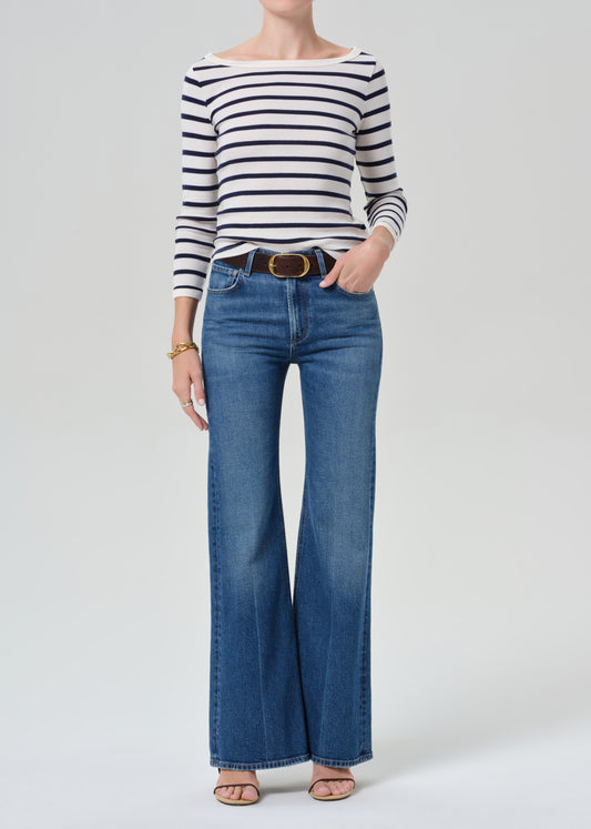 Person wearing a striped shirt and blue jeans on a grey background