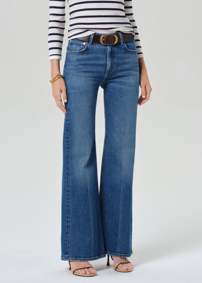 Person wearing a striped shirt and blue jeans on a grey background