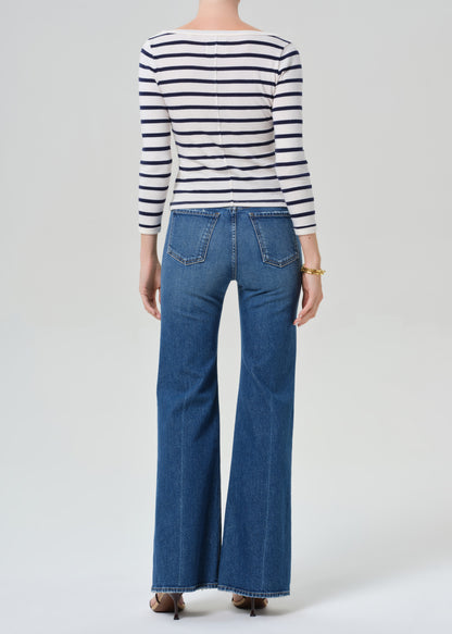 Person wearing a striped shirt and blue jeans on a grey background