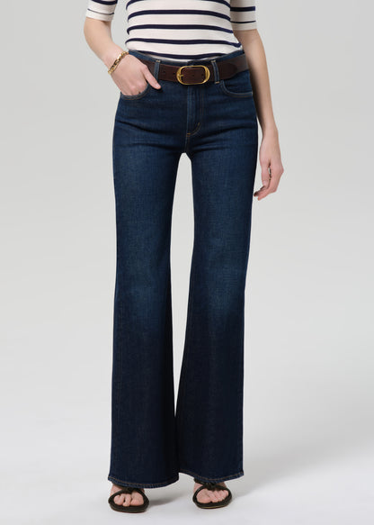 Person wearing a striped shirt and blue jeans on a plain background