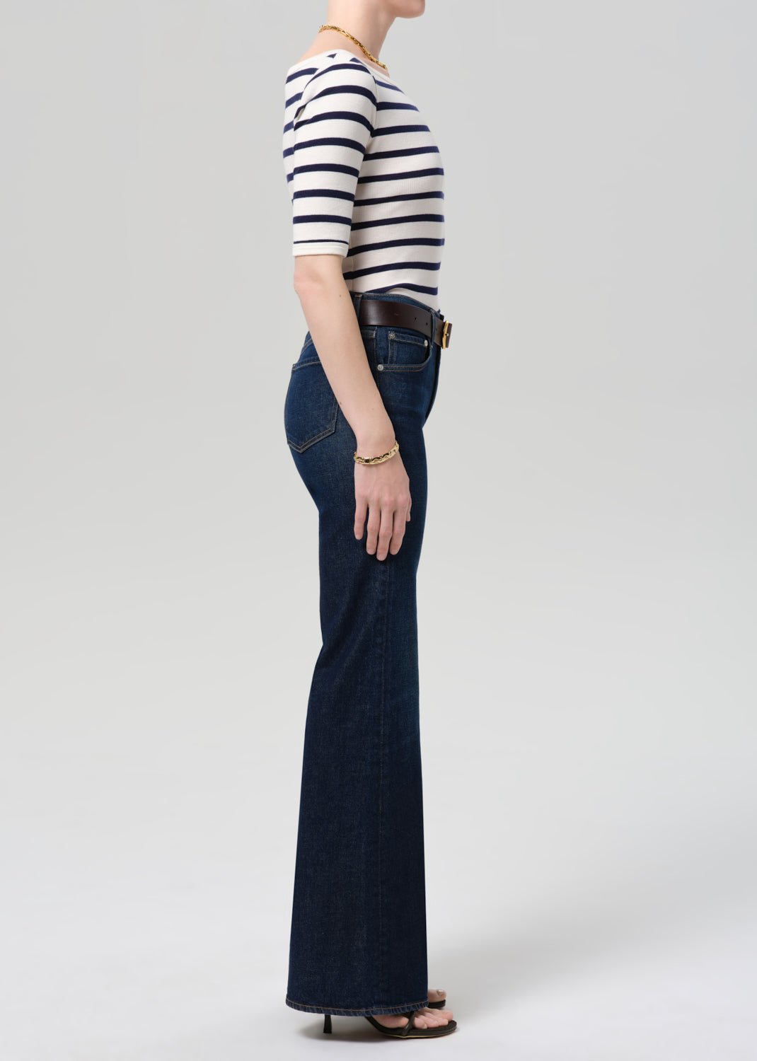 Person wearing a striped shirt and blue jeans on a plain background