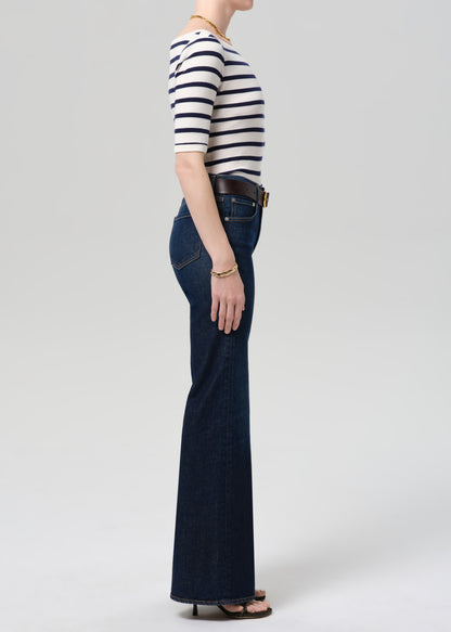 Person wearing a striped shirt and blue jeans on a plain background