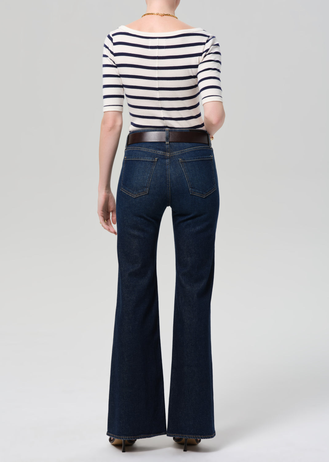 Person wearing a striped shirt and blue jeans on a plain background