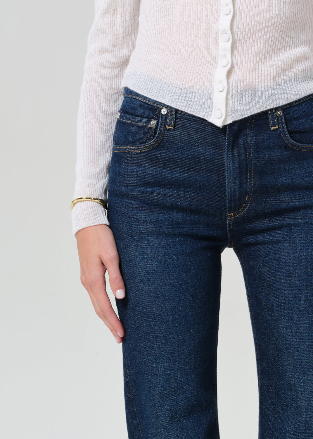 Person wearing white cardigan and dark blue jeans