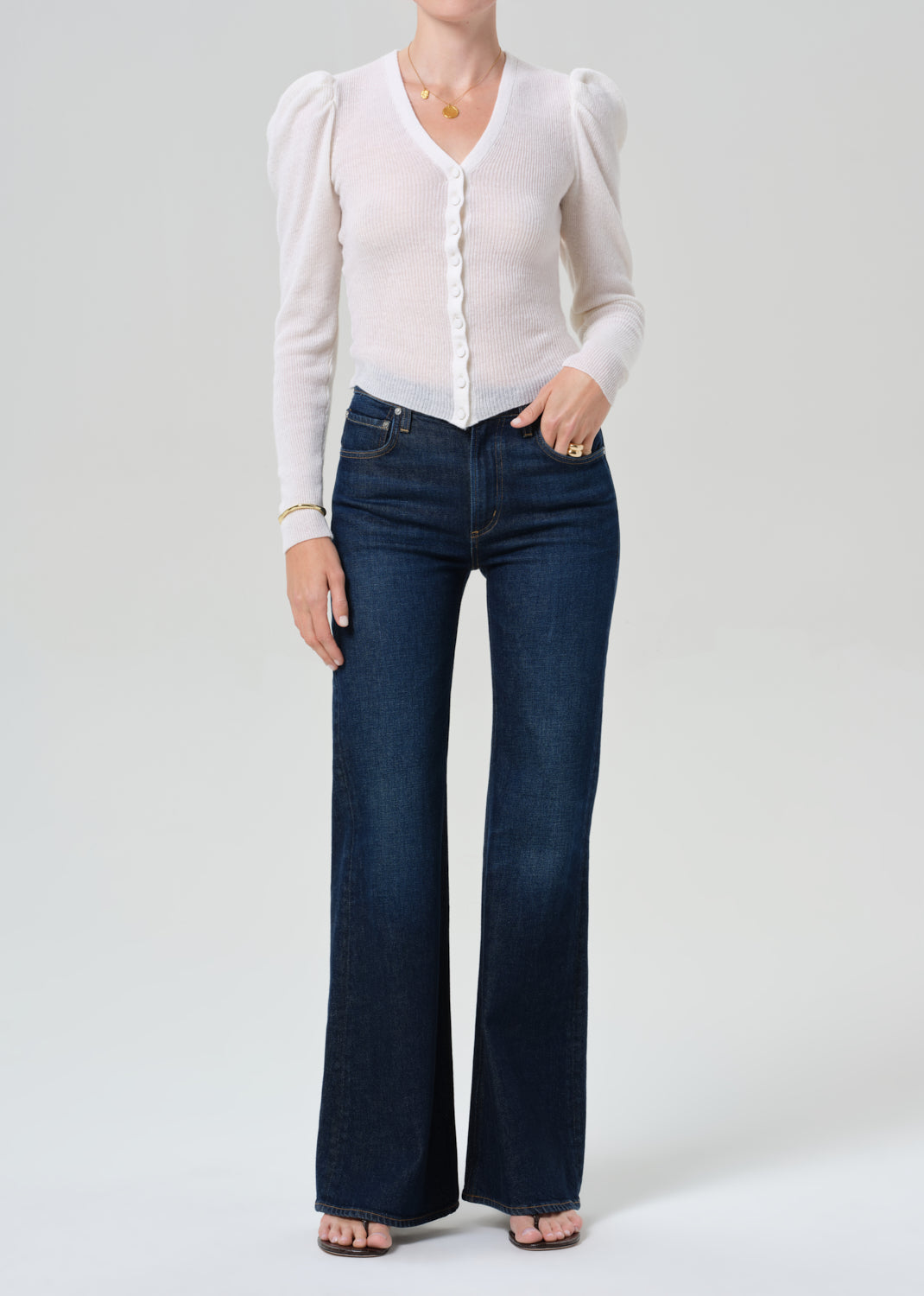 Person wearing white cardigan and dark blue jeans