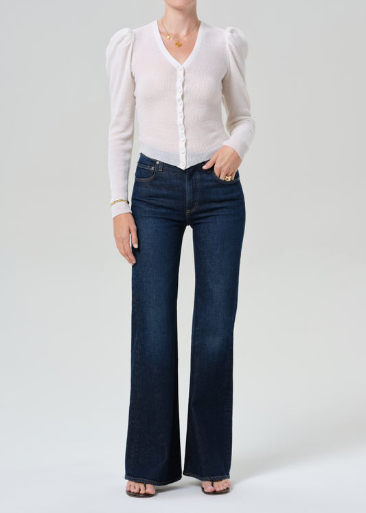 Person wearing white cardigan and dark blue jeans