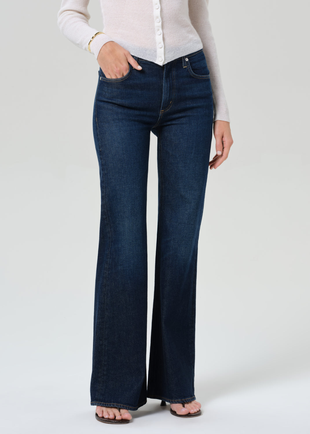 Person wearing white cardigan and dark blue jeans