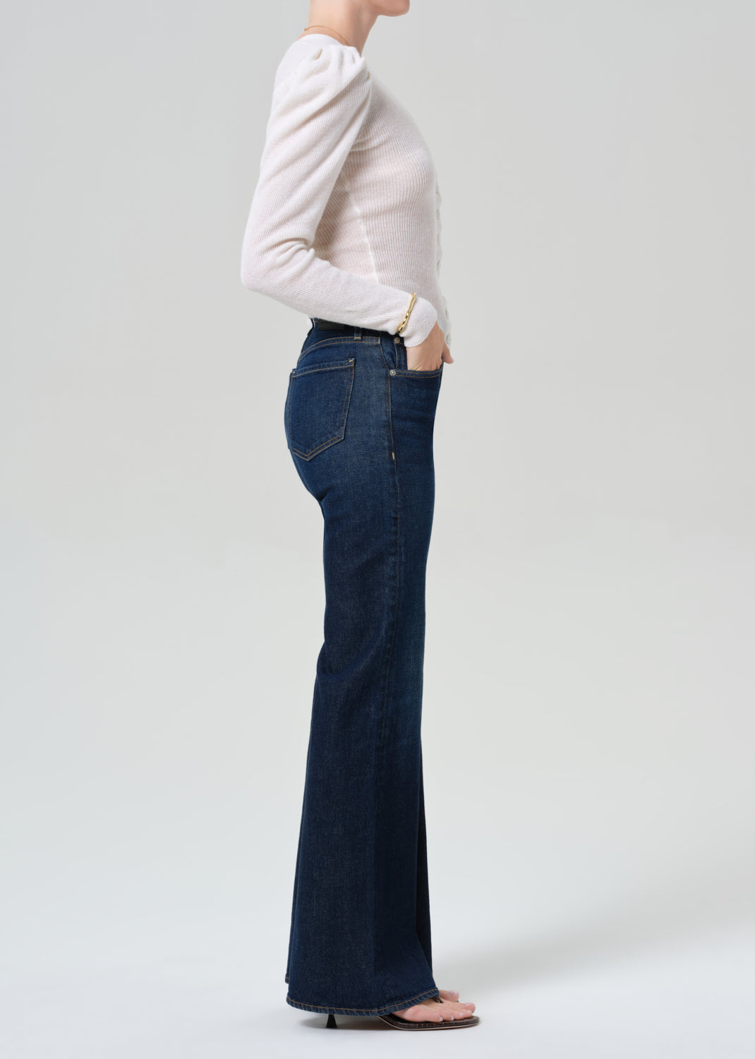 Person wearing white cardigan and dark blue jeans