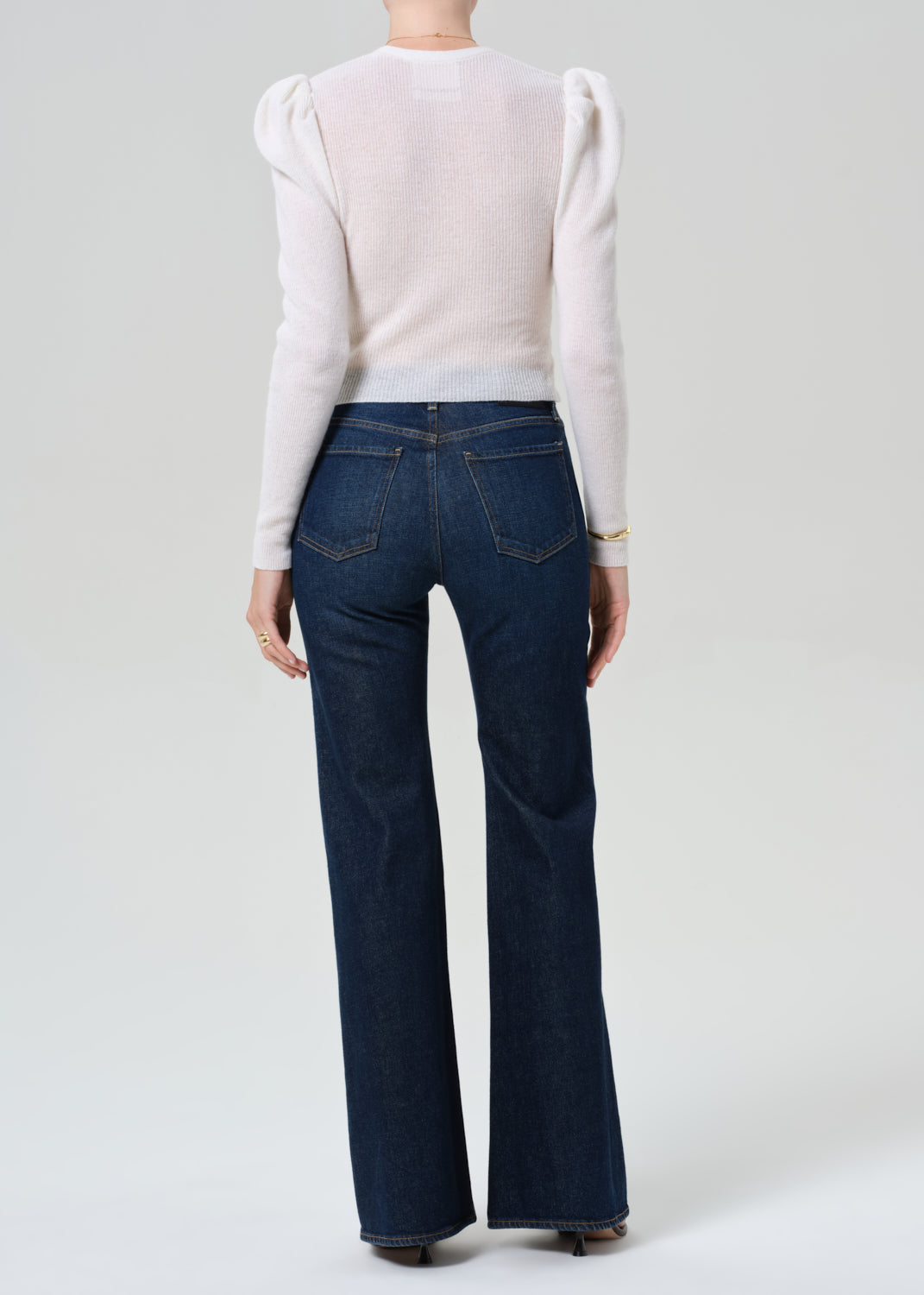 Person wearing white cardigan and dark blue jeans