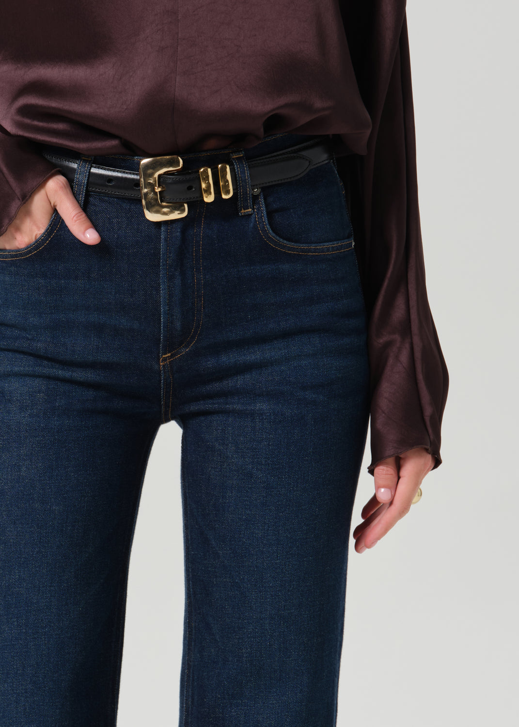 Close-up of a dark brown long sleeve draped blouse on a grey background