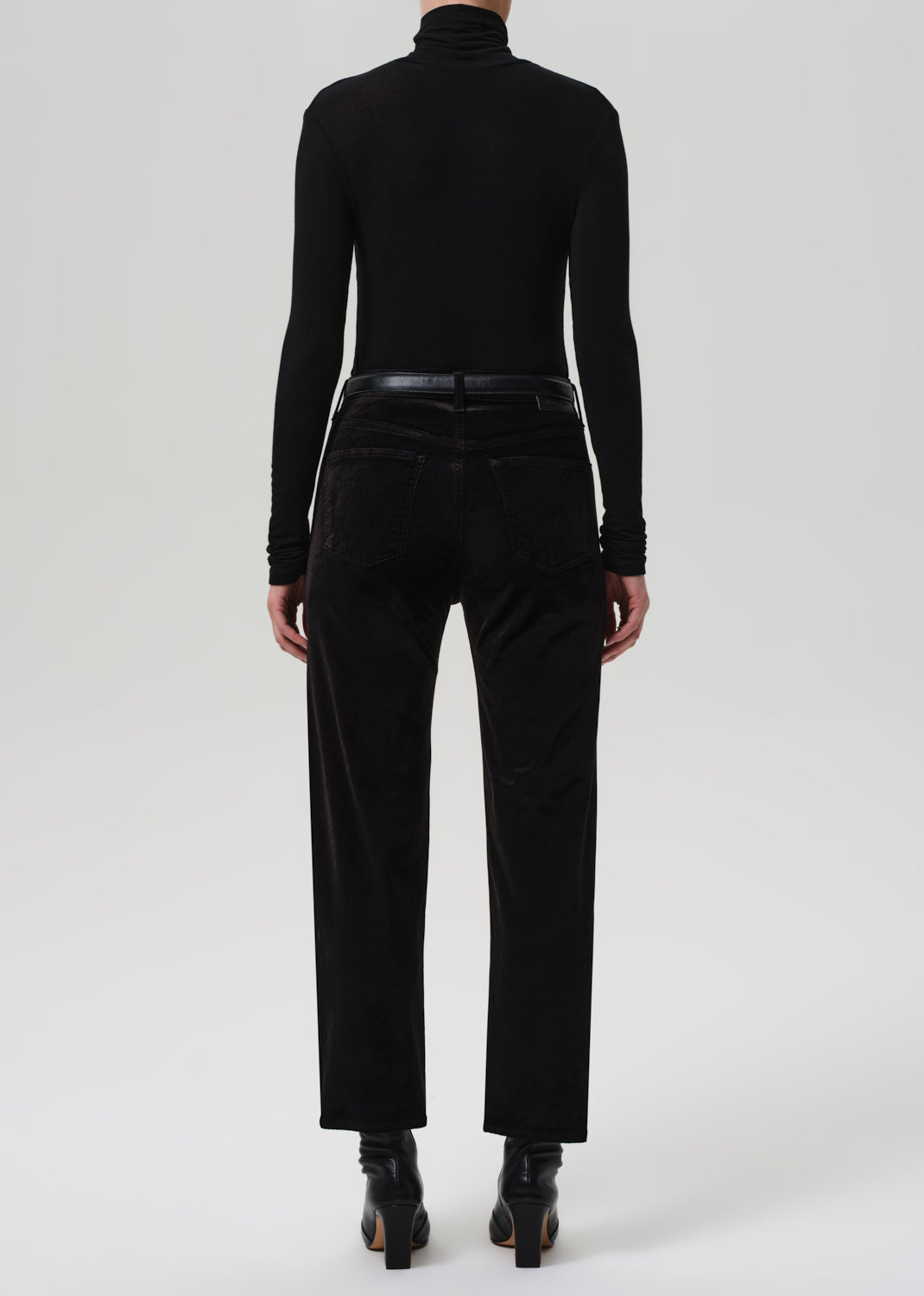 Person wearing a black turtleneck and black pants on a white background