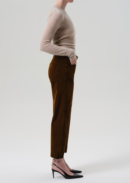 Person wearing a beige sweater and brown velvet pants on a grey background
