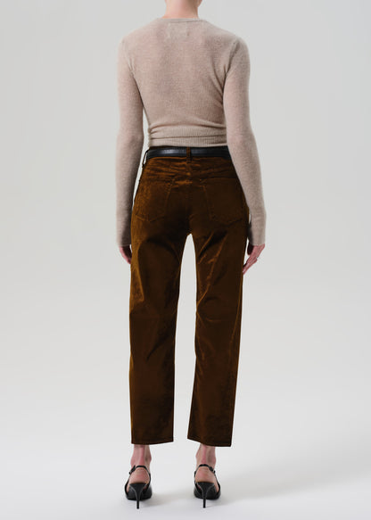 Person wearing a beige sweater and brown velvet pants on a grey background
