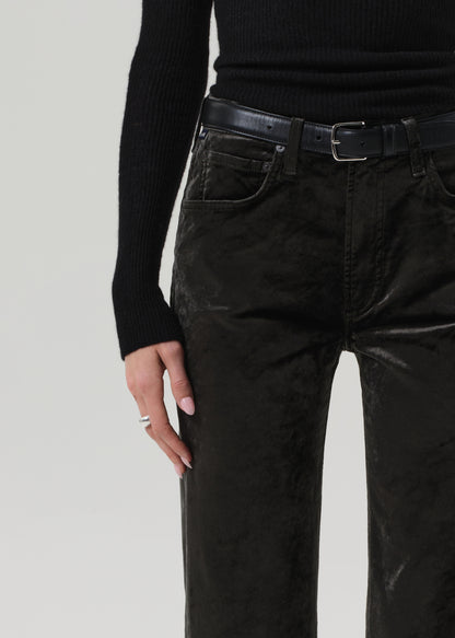 Person wearing a black turtleneck and green velvet pants on a grey background