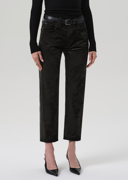 Person wearing a black turtleneck and green velvet pants on a grey background