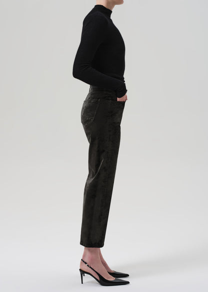 Person wearing a black turtleneck and green velvet pants on a grey background