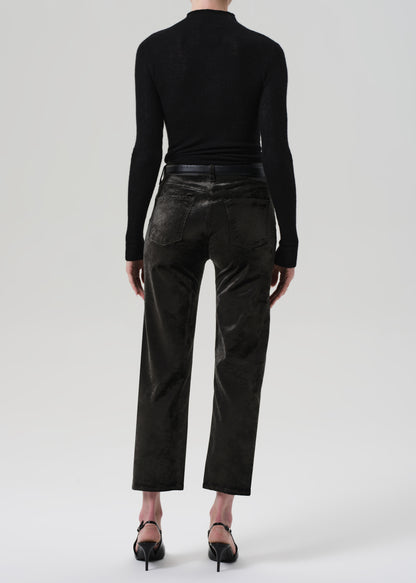 Person wearing a black turtleneck and green velvet pants on a grey background