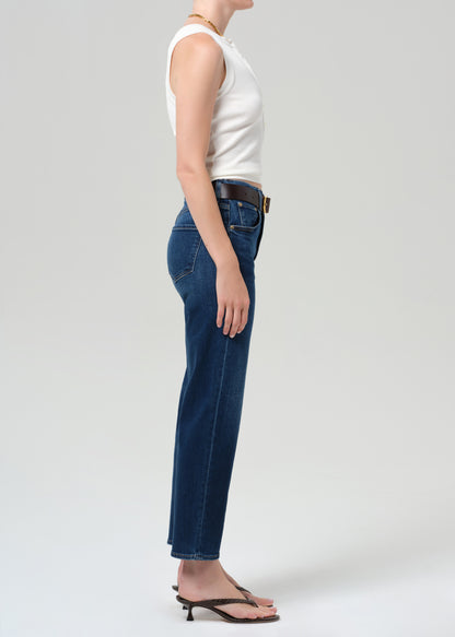 Person wearing blue jeans and a white top on a plain background