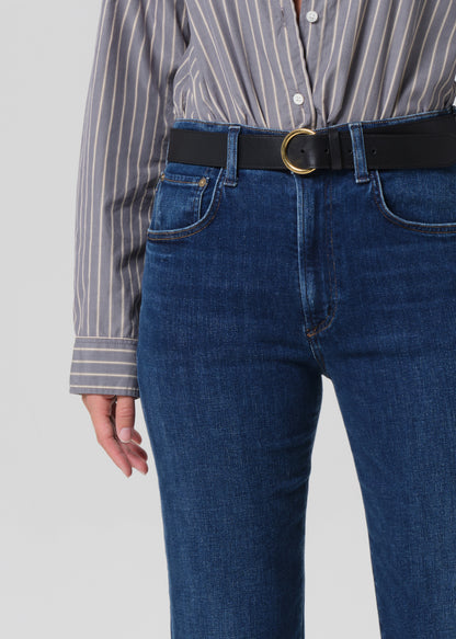 Person wearing a striped shirt and blue jeans with a black belt on a plain background