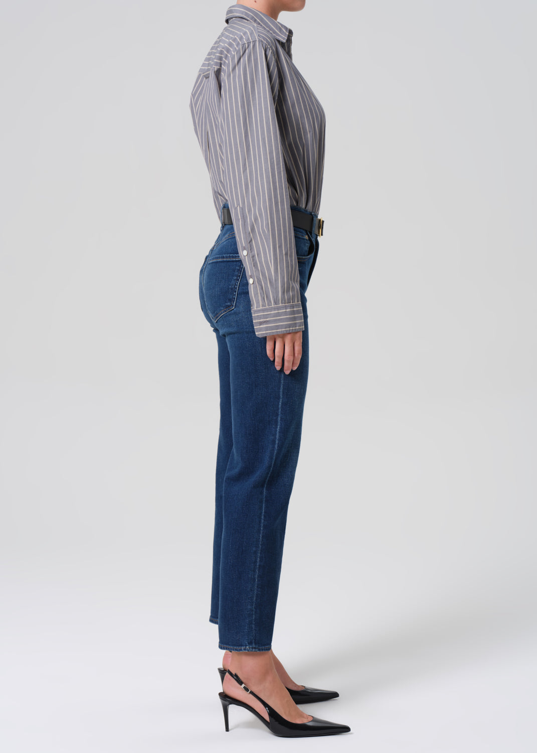 Person wearing a striped shirt and blue jeans on a white background