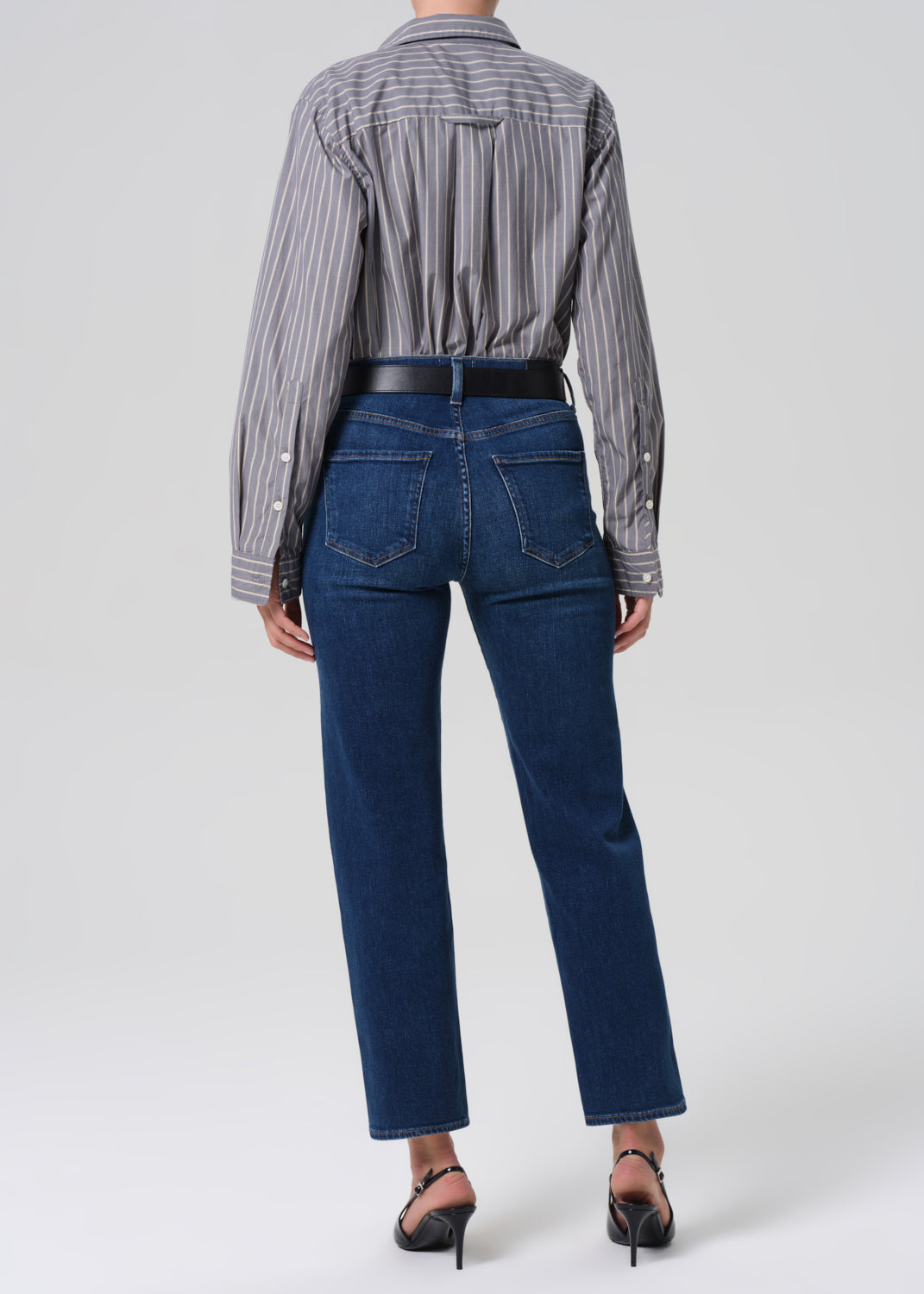 Person wearing a striped shirt and blue jeans on a white background
