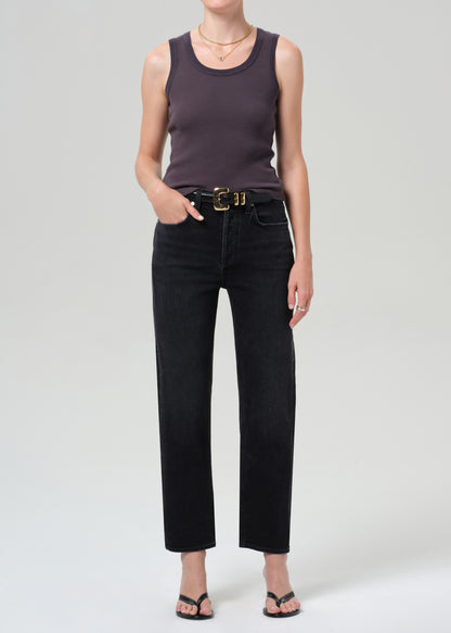 Person wearing a dark tank top and black jeans on a grey background