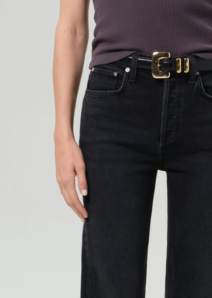 Person wearing a sleeveless top and black pants on a grey background