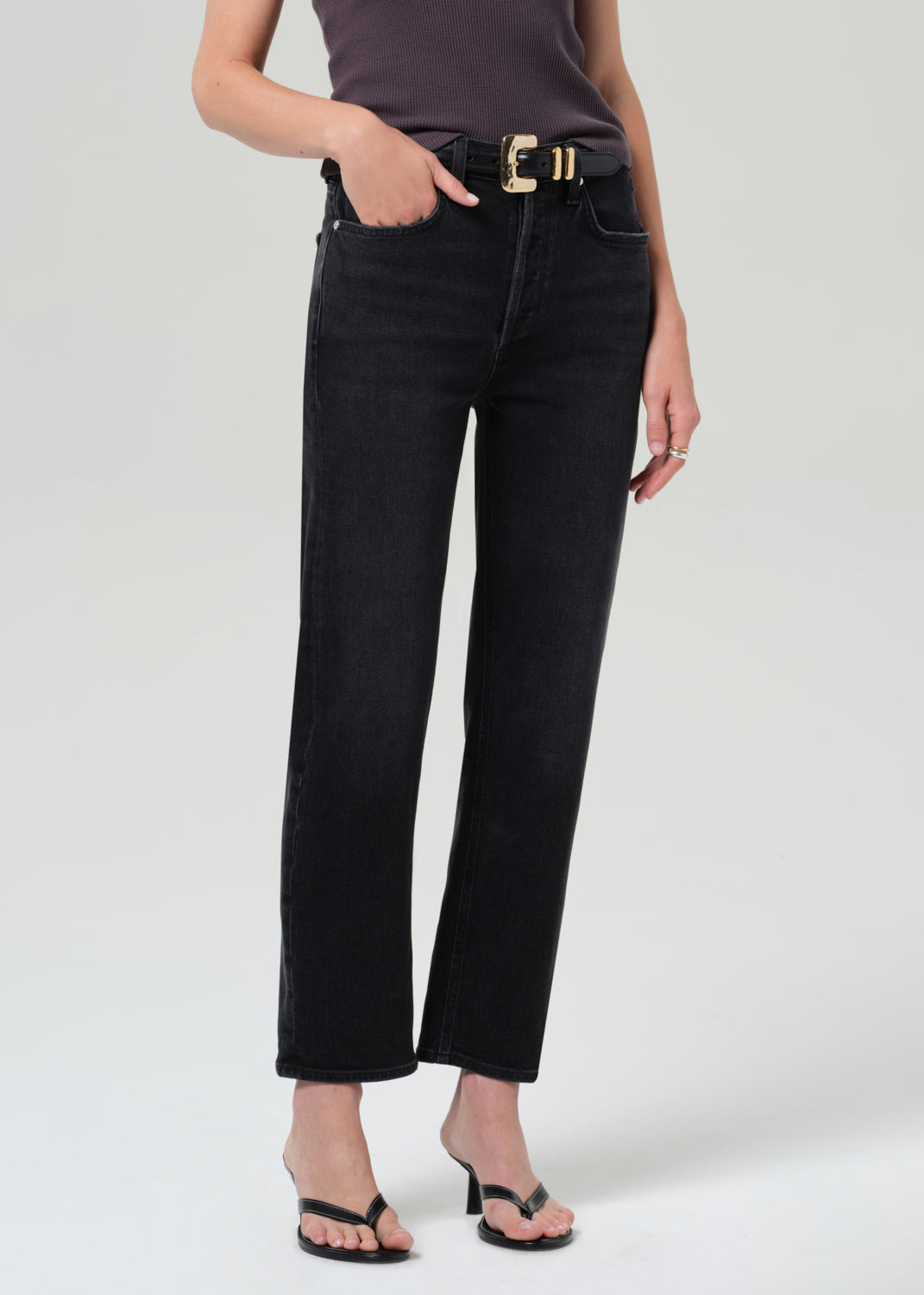 Person wearing a sleeveless top and black pants on a grey background