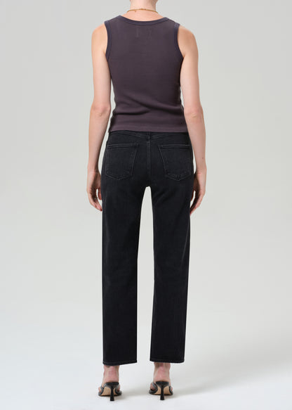 Person wearing a sleeveless top and black pants on a grey background