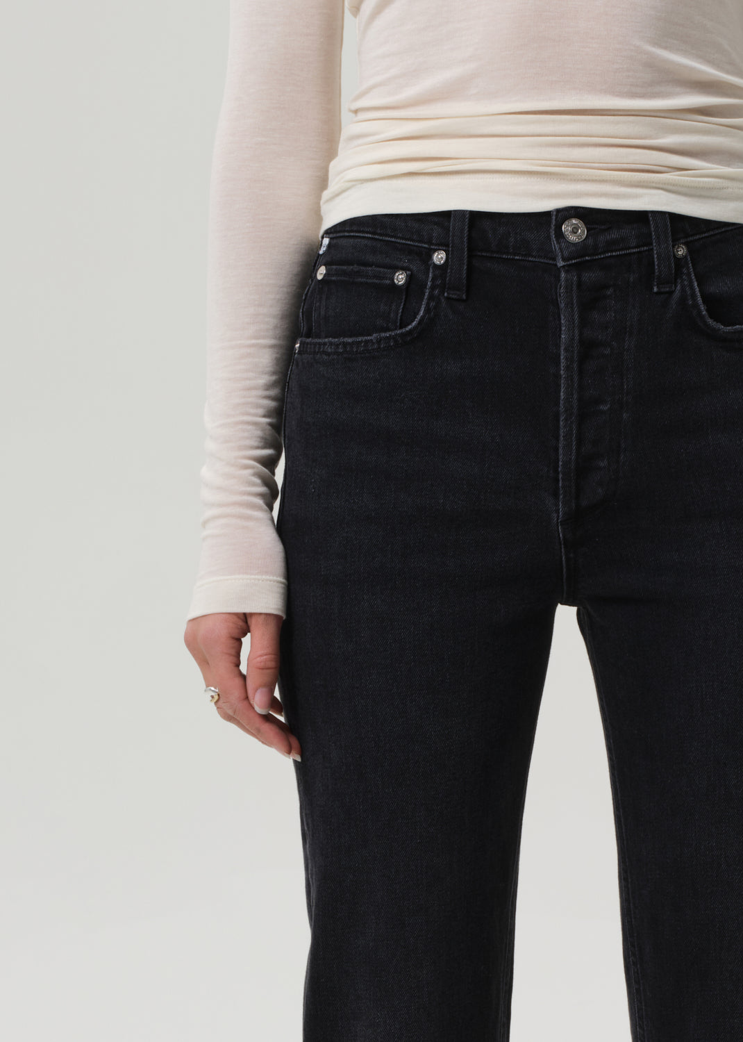 Person wearing black jeans and a white long-sleeve shirt on a plain background