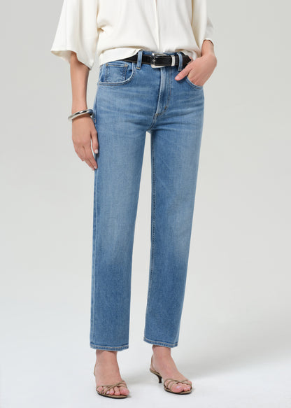 Person wearing blue jeans and a white top on a plain background