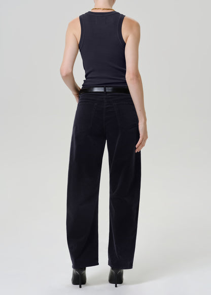A model shown from the back wearing a dark navy sleeveless top, black wide-leg trousers, and black heels against a light gray studio background.