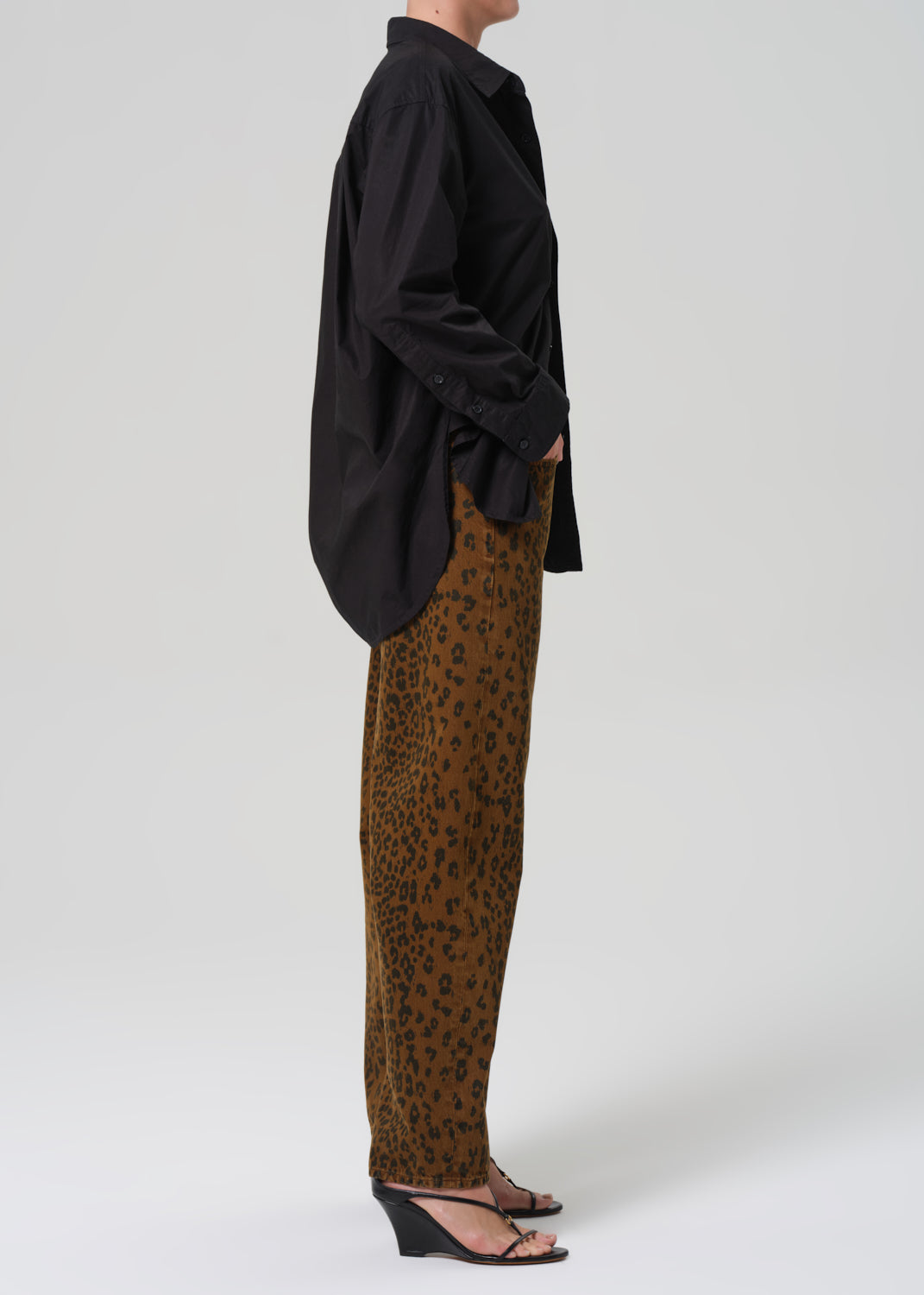 Person wearing a black oversized shirt and cheetah print pants on a white background