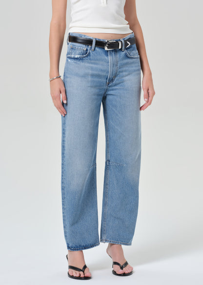 Person wearing light blue jeans and a white top on a plain background