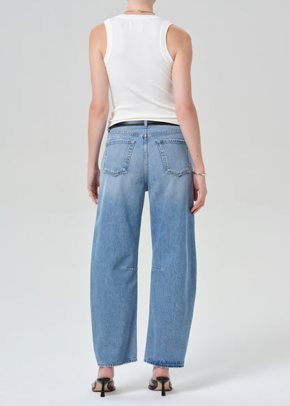 Person wearing light blue jeans and a white sleeveless top on a plain background