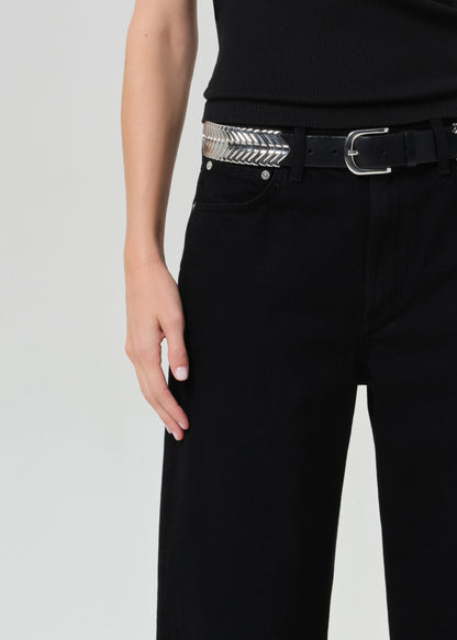 Person wearing a black sleeveless top and black jeans on a plain background