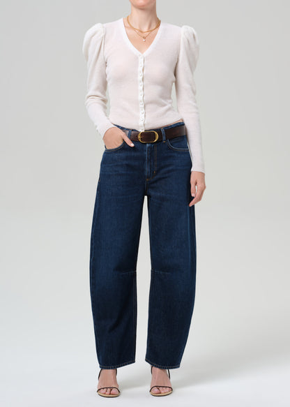 Person wearing a white blouse and blue jeans on a plain background