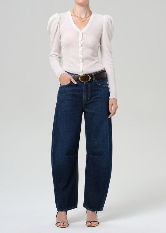 Person wearing a white blouse and blue jeans on a plain background