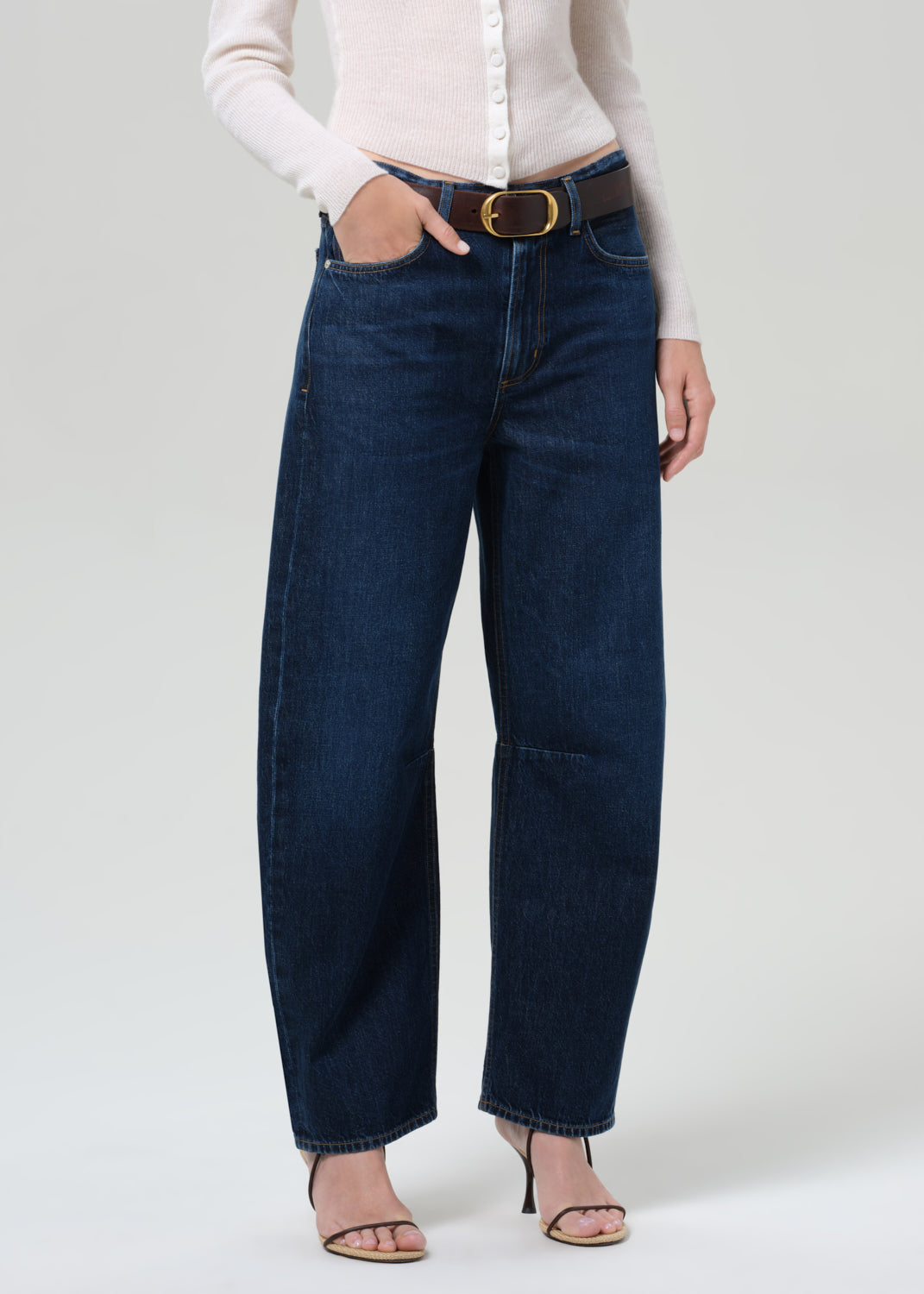 Person wearing dark blue jeans with a white shirt on a light gray background