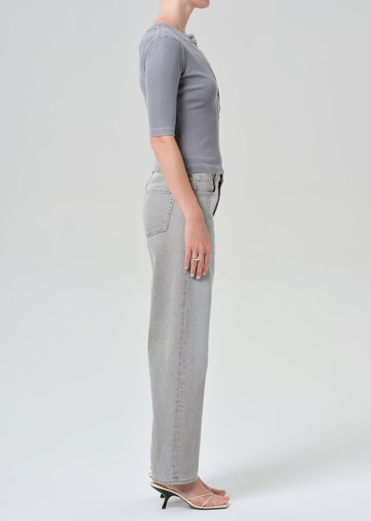 Person wearing a gray top and light gray jeans on a plain background