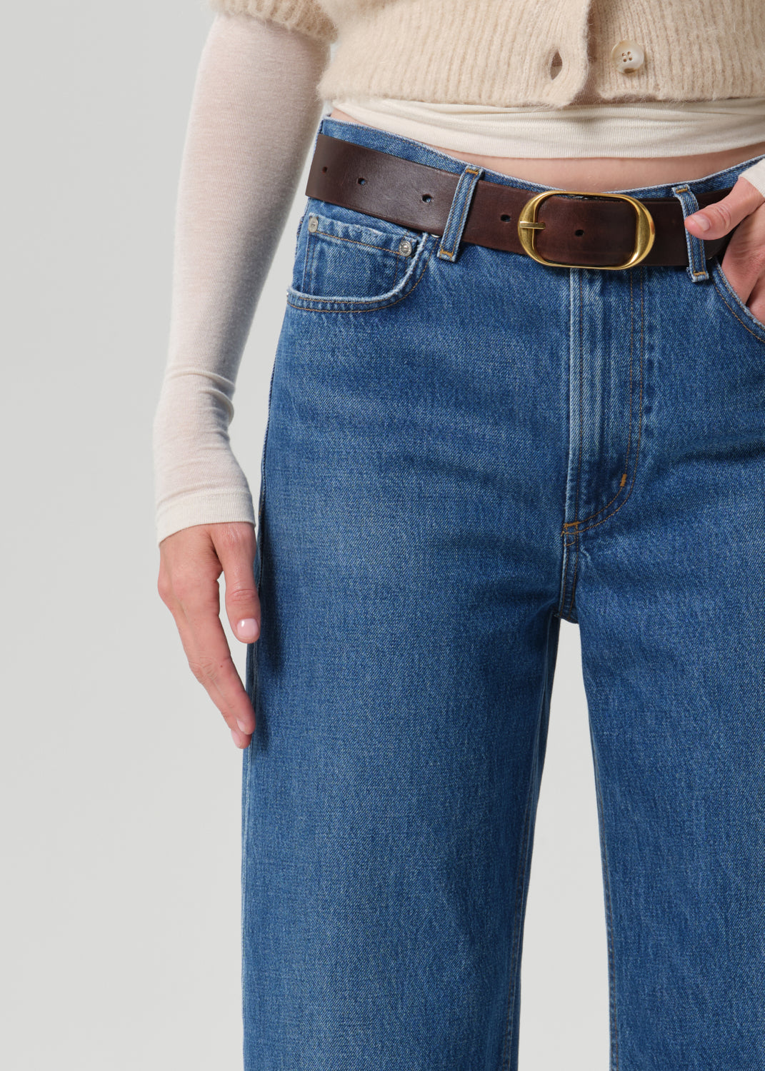 Close up of blue pant and brown belt on grey background