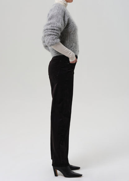 Person wearing a gray sweater and black velvet pants on a grey background