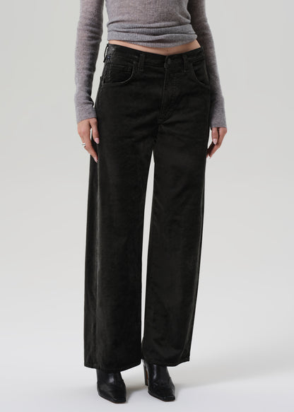 Person wearing a gray sweater and green wide-leg velvet pants on a grey background